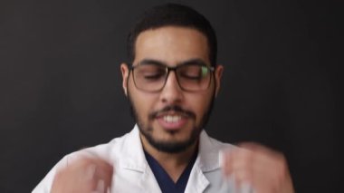 Gözlüklü Afro-Amerikalı bir adam elleriyle dans ediyor.