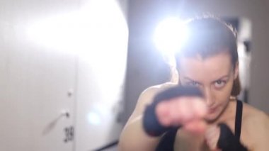 Spor salonunda antrenman yaparken yumruk pratiği yapan atletik bir kadın..