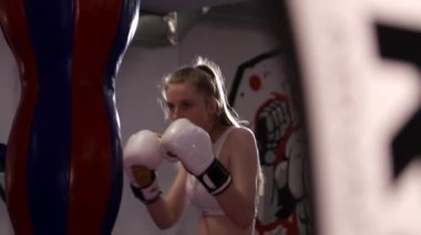Boks eldivenli güçlü bir kadın spor salonundaki torbayı yener. Kadın boksu..