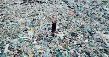 Çöplükteki adam. Okyanus sahilinde çöp. Çevre kirliliği. Çevresel sorun.