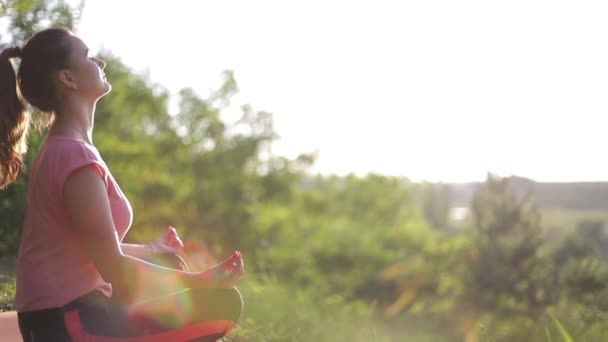 A menina relaxa e descansa ao pôr do sol, relaxando na natureza. — Vídeo de Stock