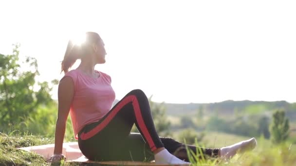 A menina relaxa e descansa ao pôr do sol, relaxando na natureza. — Vídeo de Stock