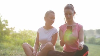 Şehir parkında iki kadın akıllı telefon kullanıyor ve birbirleriyle iletişim kuruyorlar..