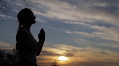 Mavi günbatımı arka planında yoga yapan kadın.