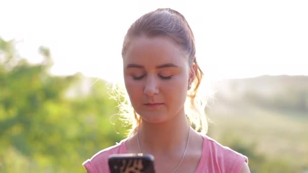 Jovem usa um smartphone para um parque da cidade — Vídeo de Stock