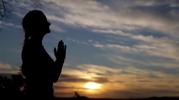 Silueta de una mujer cristiana rezando al atardecer, al aire libre — Vídeos de Stock