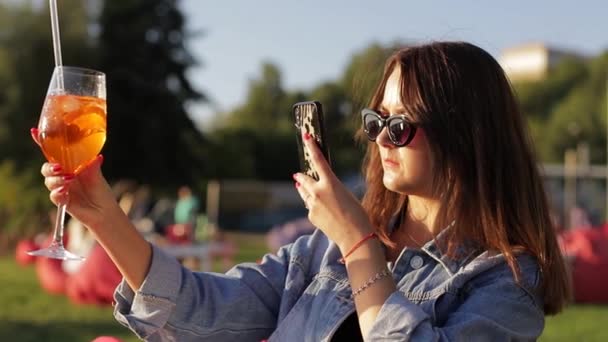 블로거는 휴대폰을 카페에서 칵테일 사진을 찍는다 여자가 스마트폰으로 사진을 찍는다 — 비디오