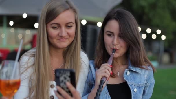 Duas Garotas Fumam Narguilé Olham Pela Foto Jovens Sentados Pôr — Vídeo de Stock