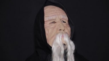 Siyah arka planda yaşlı bir adam maskesi takmış..