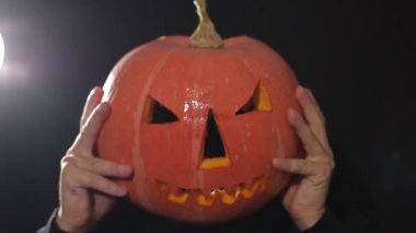 Cadılar Bayramı kutlaması için hazırlık. Cadılar Bayramı kutlaması için balkabağı kesme işlemi. Adam elleri balkabağını yavaş çekimde kesiyor..