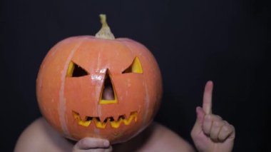 Cadılar Bayramı kutlaması için hazırlık. Cadılar Bayramı kutlaması için balkabağı kesme işlemi. Adam elleri balkabağını yavaş çekimde kesiyor..