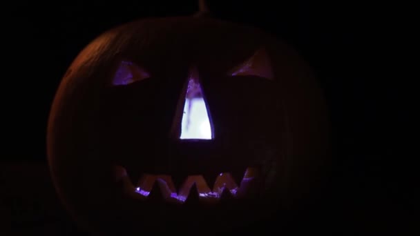 Scary Halloween pumpkins isolated on a black background. Scary glowing faces trick or treat — Stock Video