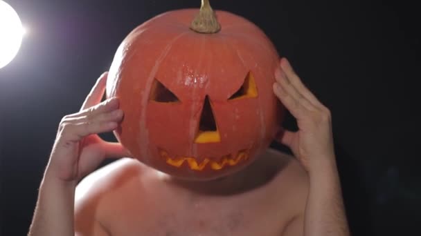 Vorbereitungen für die Feier von Halloween. Prozess des Kürbisschnitts für die Halloween-Feier. Mann schneidet Kürbis in dunklen Raum in Zeitlupe. — Stockvideo