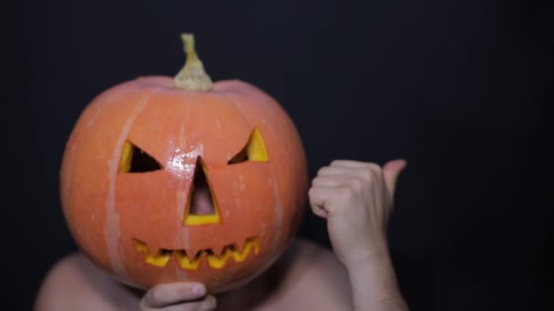 Un hombre con una calabaza en la cabeza levanta el pulgar. Lugar para la publicidad — Vídeo de stock