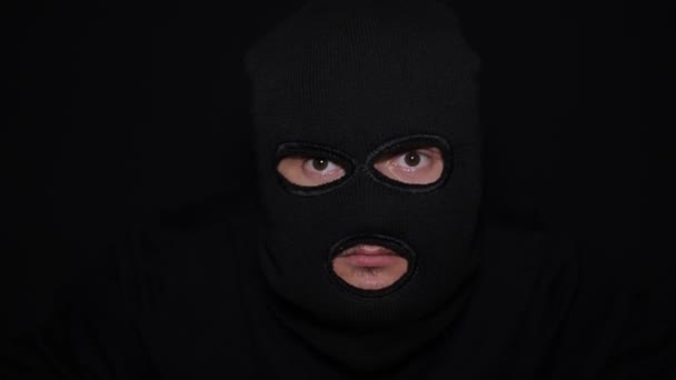 En man i svarta kläder, en mask och handskar som tar sig in, ser sig omkring och stjäl skulpturerna. En rolig och dum rånare. — Stockvideo