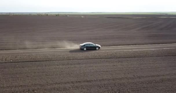 車は田舎の道を走っていて、ほこりっぽい景色を吹いている。 — ストック動画