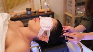 Profesyonel terapist, göz maskesi takan bir müşteriyle sağlık merkezlerine kafa bakımı yapıyor..