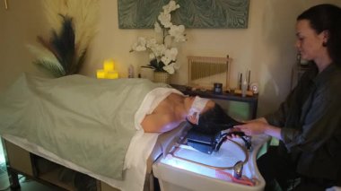 Rahatlatıcı sağlık tedavisi sırasında kadın maskesiyle spa yatağında dinleniyor..