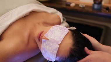 Kadın spa tedavisi sırasında göz maskesi ve havluyla dinleniyor..