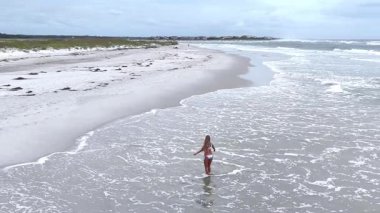 Okyanus dalgalarıyla çevrili sığ sularda duran genç bir kadının robot görüntüsü. Sahil hayatının huzurlu bir yaz anı..