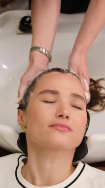 Kuaför, kuaför koltuğunda oturan müşterinin uzun düz saçlarını kesmek için makas kullanıyor. Profesyonel güzellik ve bakım hizmeti..