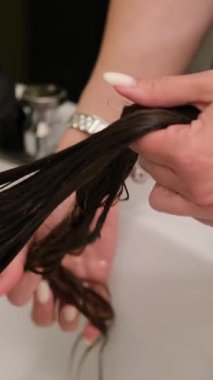 Kuaför, profesyonel güzellik salonundaki saç kesiminden önce müşterinin uzun saçlarını tarıyor ve hizalıyor..