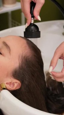 Modern güzellik salonunda saç kesimi için müşterinin uzun saçlarını tarayıp hazırlayan profesyonel bir kuaför. Saç bakımı ve bakım sahnesi.