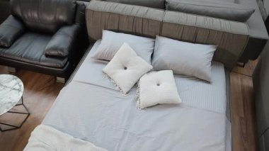 Bir bayan müşterinin dekoratif yastıklarla bir yatağa uzanmış modern bir mobilya mağazasındaki yatağın rahatlığını kontrol ederken çekilmiş üst görüntüsü..