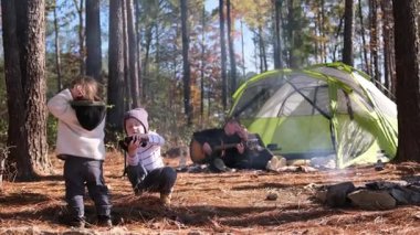 İki çocuk kamp ateşinin yanında oynarken aileleri ormanda kamp yaparken çadır kuruyor. Dışarıda aile bağlarının olduğu yaşam tarzı..