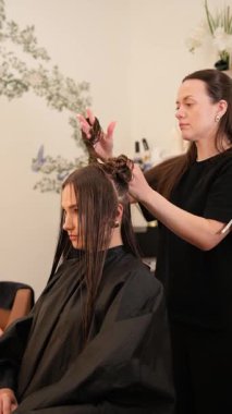 Modern güzellik salonunda saç kesiminden önce kadın müşterinin uzun saçlarını kesen profesyonel kuaför..