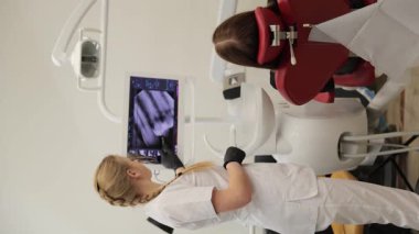 Bir dişçi modern bir klinikte gelişmiş röntgen teknolojisi kullanarak diş muayenesi yapar. Olay yeri oral sağlık, teşhis ve profesyonel tedaviyi vurguluyor.