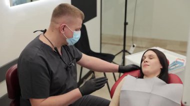 Modern bir klinikte diş muayenesi sırasında bir dişçi ve hasta. Sahne oral sağlık, tıbbi danışmanlık ve profesyonel tedavi planlamasını vurguluyor.