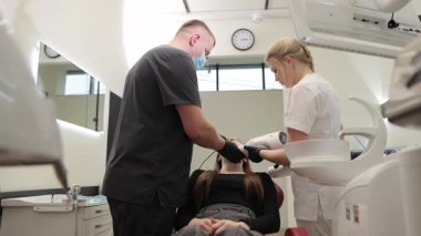 Bir doktor, deneyimli personelin parlak bir klinik ortamında gösterdiği bir diş prosedürünü gerçekleştirir..