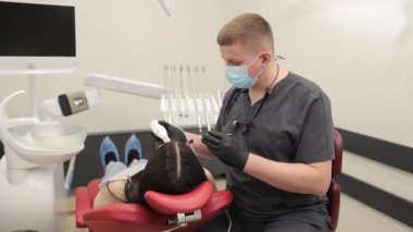 Eğitimli bir diş hekimi, klinik ortamdaki bir hastaya dişçi muayenesi yapıyor.
