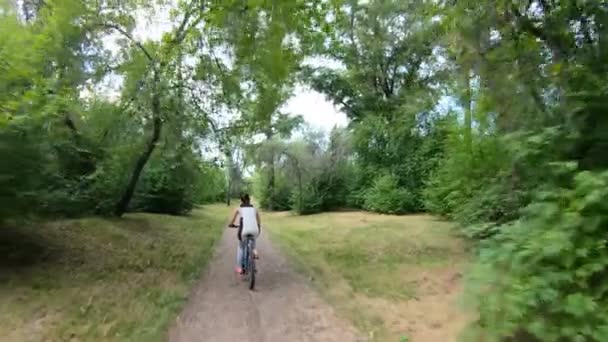 Ciclismo en el parque. Chica montando en bicicleta en un sendero forestal. Movimiento lento — Vídeos de Stock