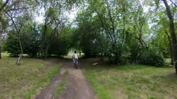 Kerékpározás a parkban. Lány lovaglás kerékpár egy erdei ösvényen. Lassú mozgás — Stock videók