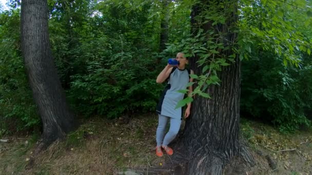 Атлет отдыхает и пьет воду в лесу — стоковое видео