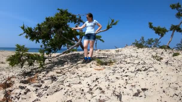 Flickan vidrör en trädgren på stranden — Stockvideo