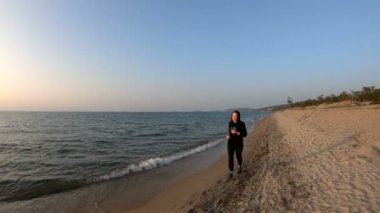 Gün batımında kumlu plajda koşan kadın koşucu