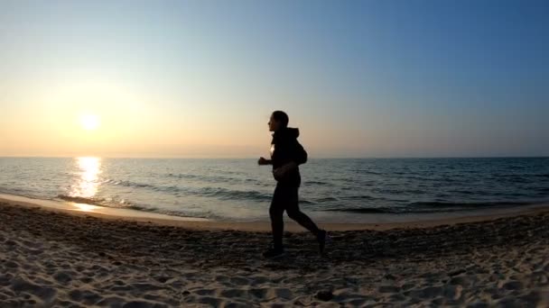 Kvinnlig löpare jogging på sandstranden vid solnedgången — Stockvideo