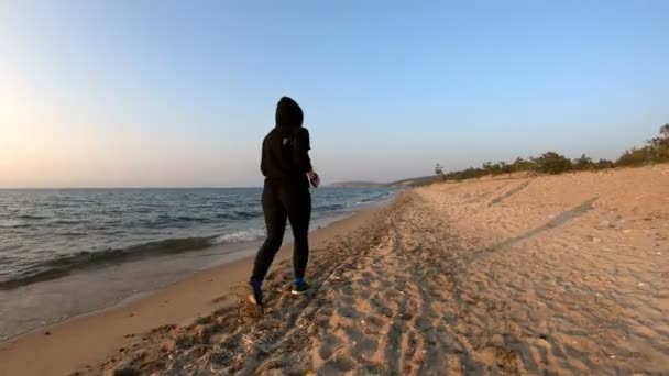 Corridore femminile che corre sulla spiaggia sabbiosa al tramonto — Video Stock