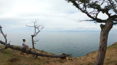 Deniz deki bir ağaçta oturan kız