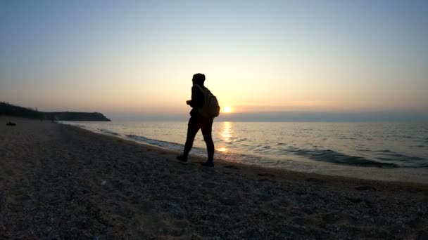 Een man loopt langs de kust bij zonsondergang — Stockvideo