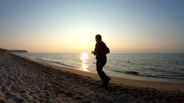 Corriendo en la playa de arena al atardecer — Vídeo de stock