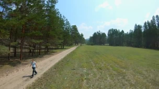 Una chica caminando por un camino rural. Disparo aéreo — Vídeos de Stock