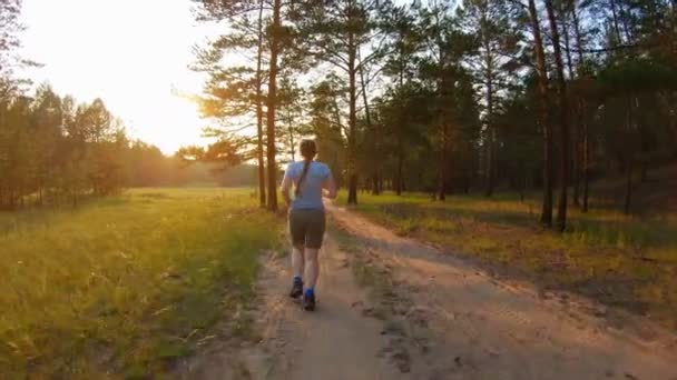 Menina correndo em uma estrada rural ao pôr do sol — Vídeo de Stock