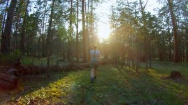 Düşmüş bir ağacın üzerinden atarak ormanda yürüyen kız