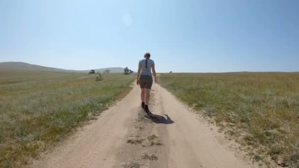 Jong meisje wandelen op een landweg — Stockvideo