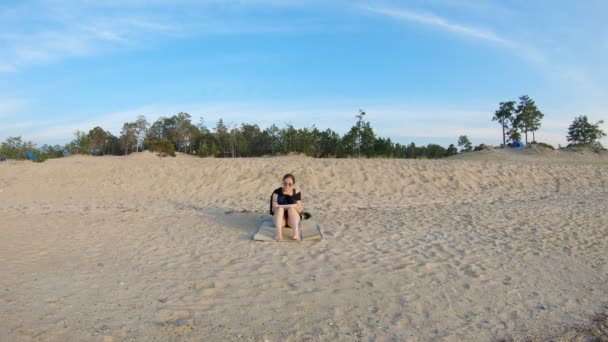 Meisje zittend op zee, op een zandstrand, en trekt — Stockvideo