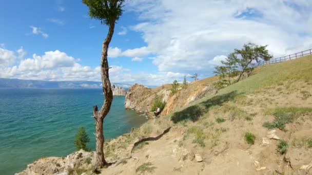 Vista aérea de una chica sentada en una costa rocosa y dibujando. Hermoso paisaje — Vídeos de Stock